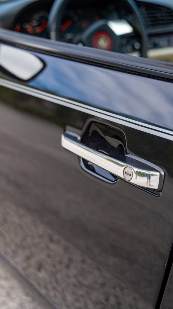Detail chrómovej kľučky dverí na čiernom Porsche 944S